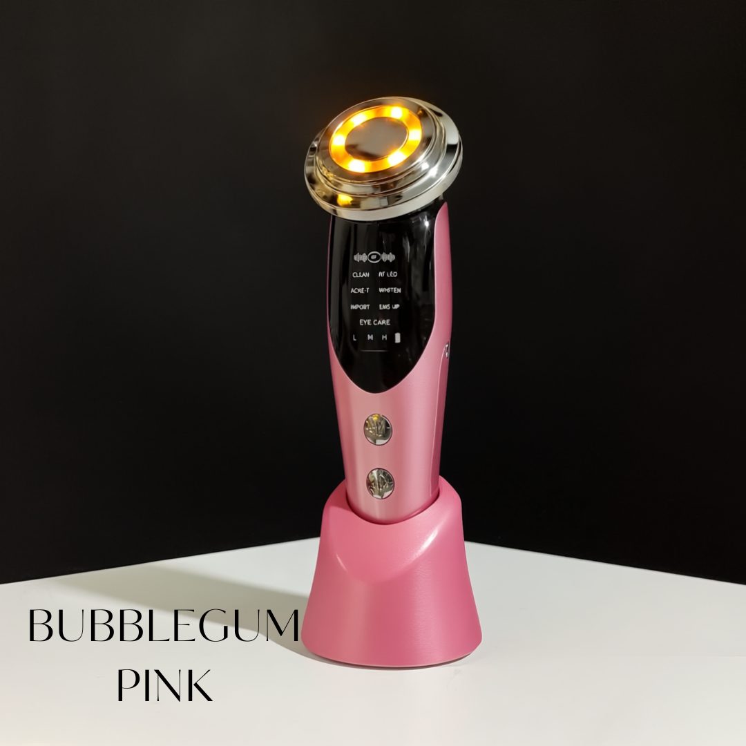 A pink handheld beauty device standing in its matching charging base on a white surface against a black wall, its ring-shaped head lit warm gold, with the words BUBBLEGUM PINK set in a serif at lower left